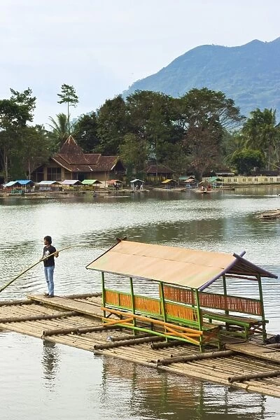 Man punting bamboo raft on Situ Cangkuang lake at this village known for its temple, Kampung Pulo, Garut, West Java, Indonesia, Southeast Asia, Asia