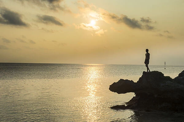 Man on a rock in backlight on the rocky west coast in Ouvea, Loyalty Islands, New Caledonia