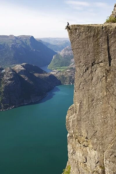 Man sitting on Preikestolen (Pulpit Rock) above fjord, Lysefjord, Norway