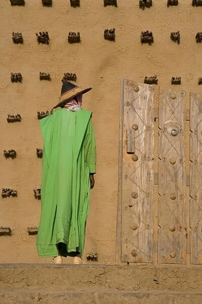 Man standing outside the Djenne Mosque, the largest mud structure in the world