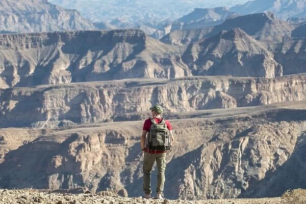 A man stands on the edge of the Fish River Canyon, Namibia, Africa
