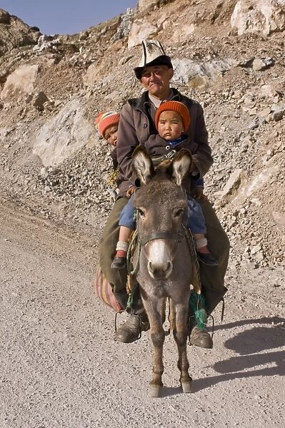 Man with twins on donkey in the mountains near Sary Tash, Kyrgyzstan, Central Asia, Asia