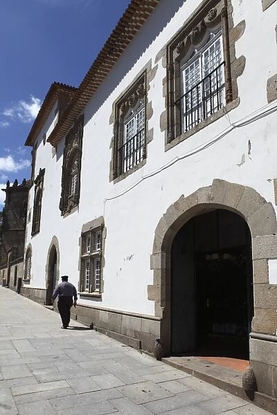 A man walks past the Manueline Coimbras House (Casa dos Coimbras) at Santa Cruz square