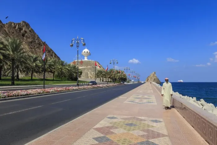Framed Print : Man wearing dishdasha walks along Mutrah Corniche with national flags, flower beds Framed Print : Man wearing dishdasha walks along Mutrah Corniche with national flags, flower beds