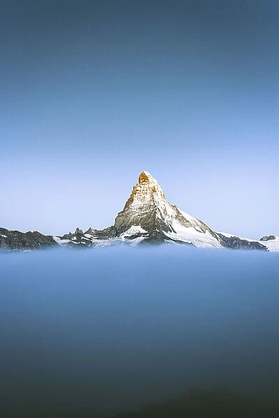 Matterhorn peak emerging from fog at dusk, Zermatt, Valais Canton, Swiss Alps
