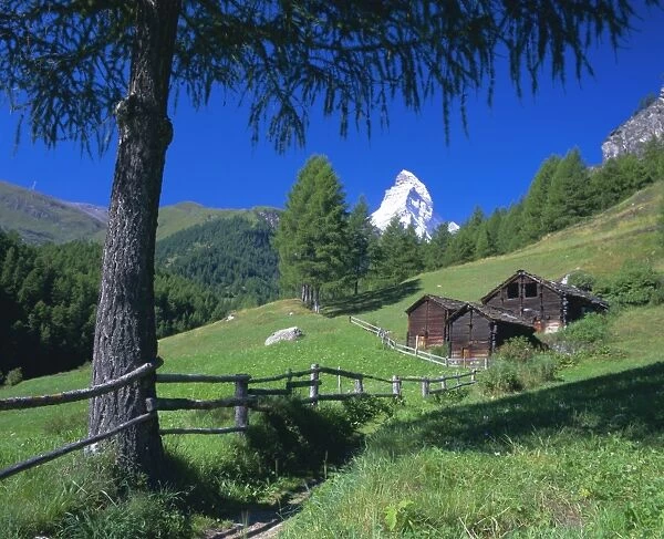 The Matterhorn towering above green pastures and wooden huts