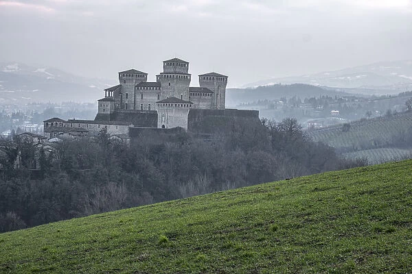 Medieval castle of Torrechiara with square towers on a hill on a foggy day, Torrechiara, Emilia Romagna, Italy, Europe