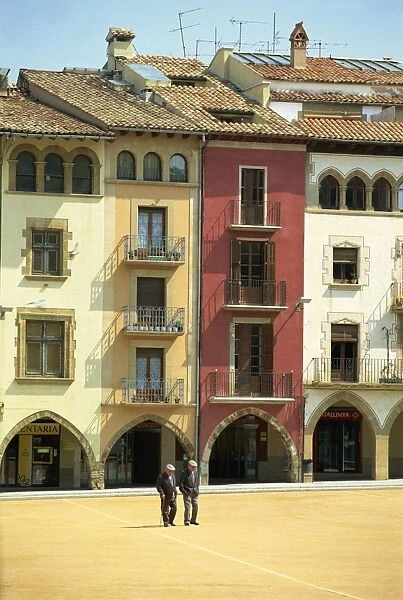 Two men cross the square of the Placa Major in the town of Vich