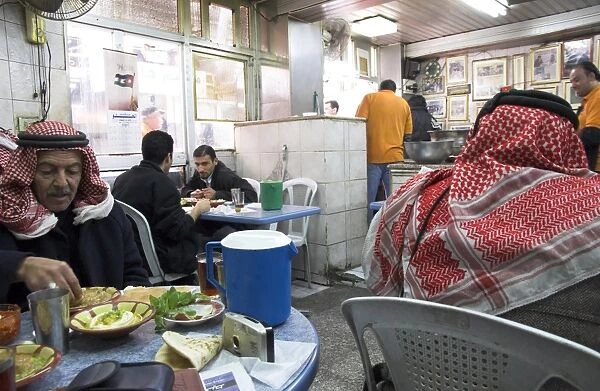 Men in keffiyeh eating traditional humus in Hashem restaurant