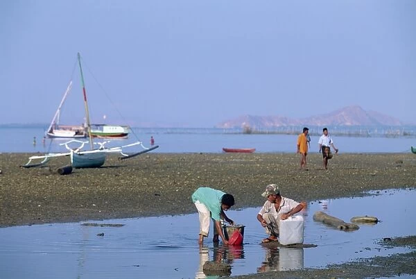 Men and outrigger boats at low tide off the port of
