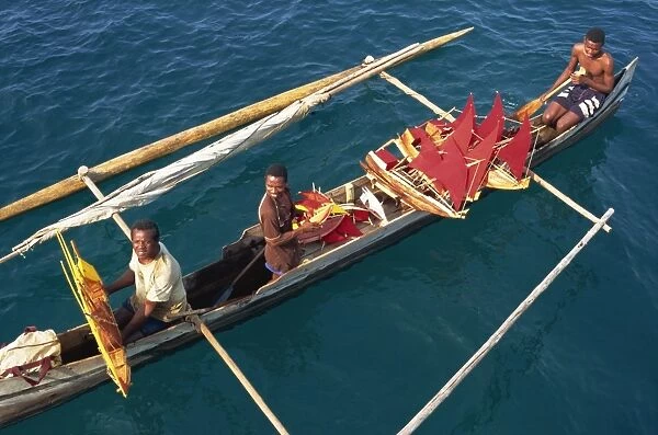 Men in outrigger canoes selling model boats with red sails, Nosy Be, Madagascar, Africa