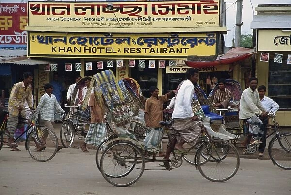Men riding cycle rickshaws on the street passing the outside of a hotel