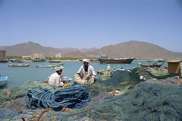 Men sitting amongst fishing nets at dockside