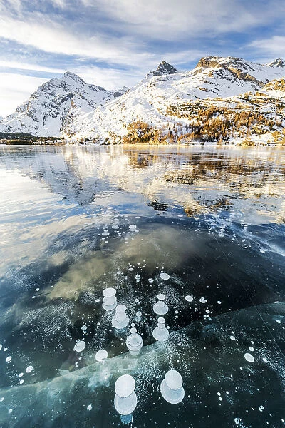 Methane bubbles in the icy surface of Silsersee with snowy peak, Lake Sils