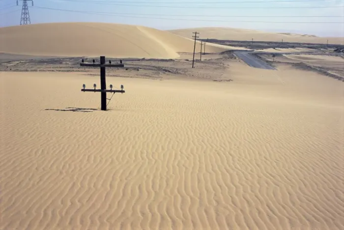 Framed Print : Migrating barchan sand dunes across road marked by buried telegraph poles Framed Print : Migrating barchan sand dunes across road marked by buried telegraph poles