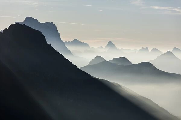 Mist on peaks of Dolomites and Monte Pelmo seen from Cima Belvedere at dawn, Val di Fassa