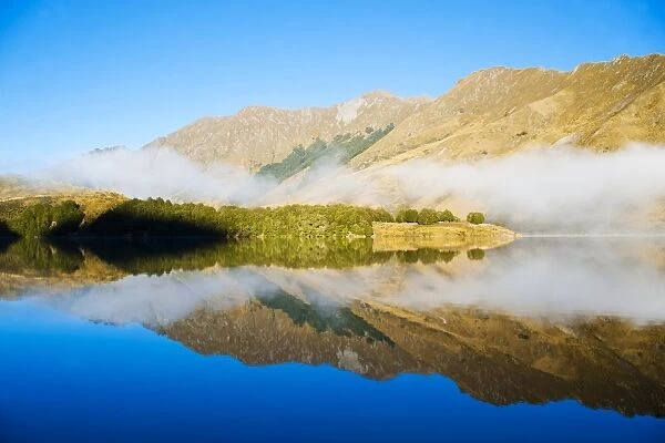 Misty dawn reflections on calm Lake Moke, Queenstown, Otago, South Island, New Zealand, Pacific