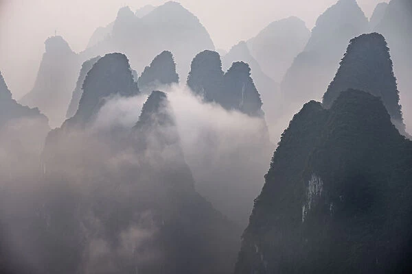 Misty morning with fog and low clouds on the peaks above Li River, Guangxi, China, Asia