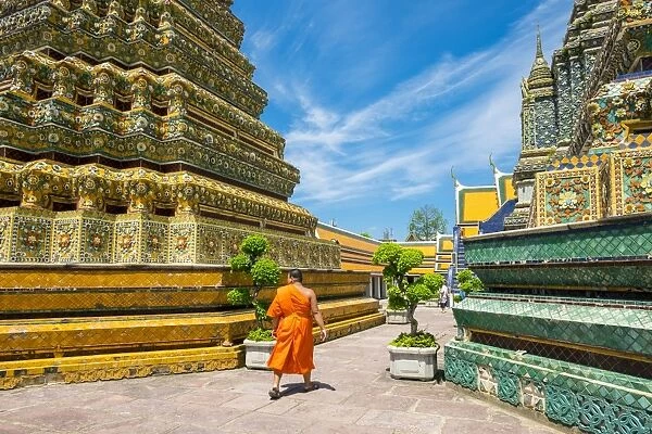 A monk walks past stupas at Wat Pho (Temple of the Reclining Buddha), Bangkok, Thailand