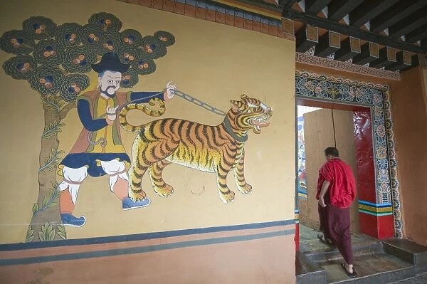 A monk walks past a tiger painting at Paro Rinpung Dzong dating from 1644