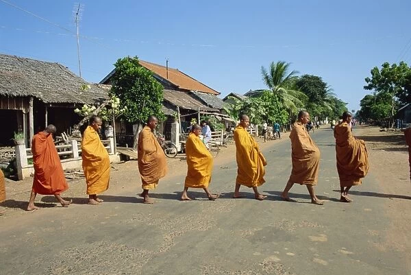 Monks with begging bowls beneath saffron robes go out in the morning in Cambodia