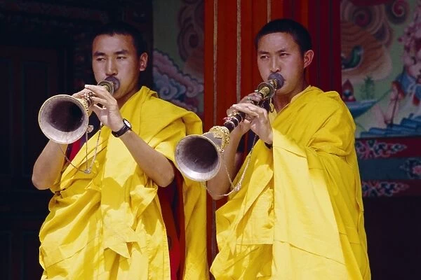 Monks blowing flutes outside a gompa (Tibetan monastery)