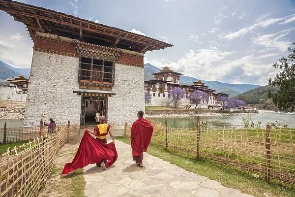 Two monks dressed in traditional red access the Punakha Dzong a former monastery