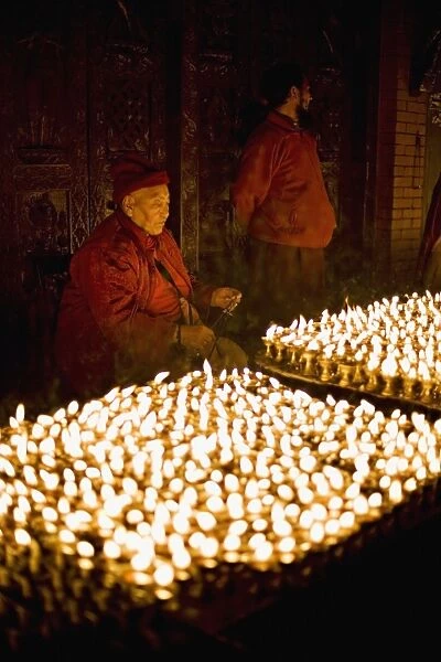 Monks light butter lamps on an auspicious night