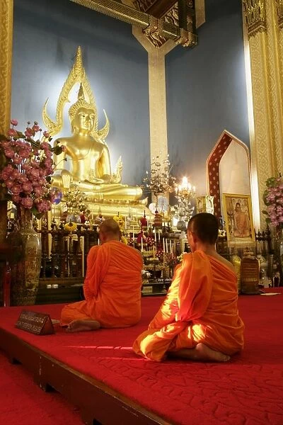 Monks praying and giant golden statue of the Buddha