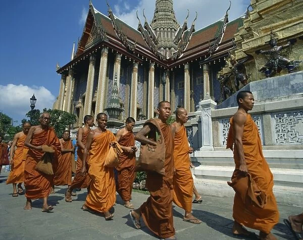 Monks in saffron robes walk past a temple in Bangkok