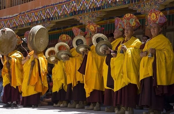 Monks standing in yellow costumes accompanying those