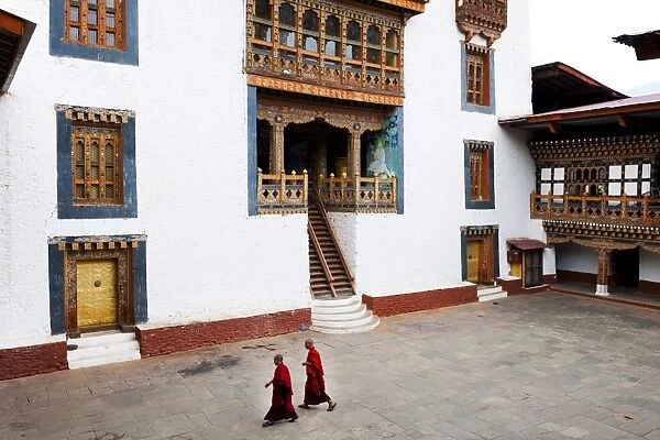 Monks walking through the courtyard of Punakha Dzong, Punakha District, Bhutan, Asia