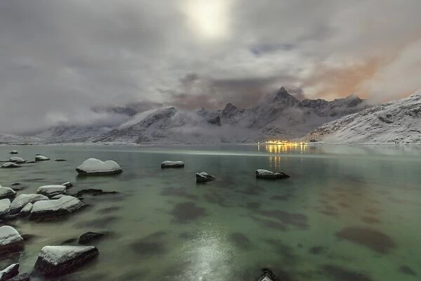 Full moon lights up the snow capped peaks reflected in the cold sea, Vareid, Flakstad