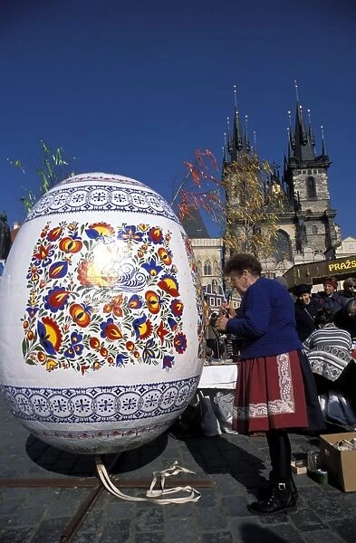 A Moravian woman decorating a large egg with Easter designs on the Old Town Square
