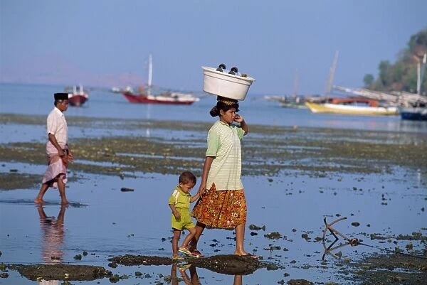 Mother and child walking at low tide off the port of Labuhanbajo