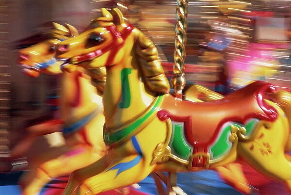 Motion blur of brightly painted merry go round (carousel) horses at speed