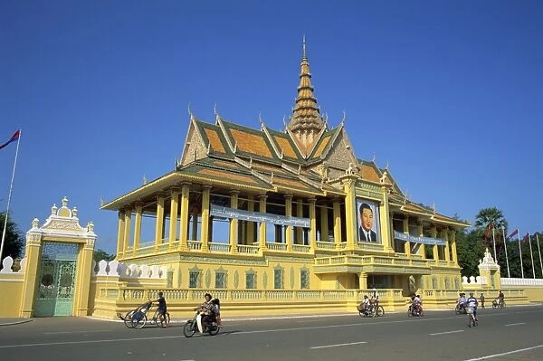 Motorbikes and bicycles passing the Royal Palace in Phnom Penh, Cambodia