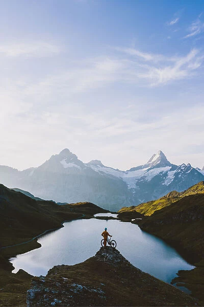 Mountain biker looking at Bachalpsee lake and Bernese Oberland mountains at dawn