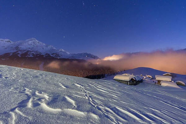 Mountain huts covered with snow under the starry winter sky, Andossi, Madesimo
