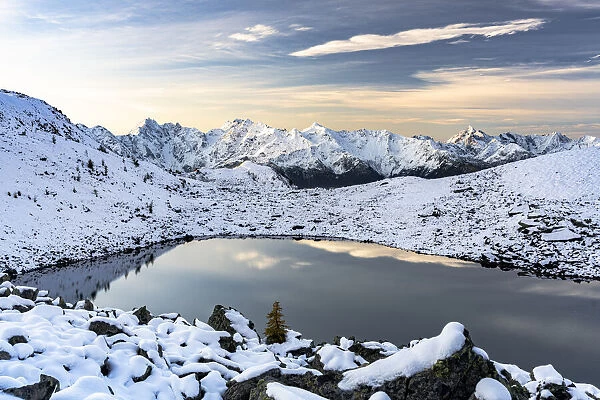 Mountain peaks of Orobie Alps covered with snow reflecting in the frozen Rogneda lake at