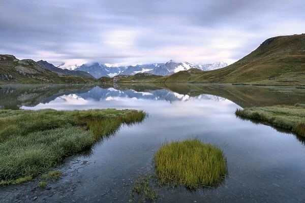 The mountain range is reflected in Fenetre Lakes at dusk, Ferret Valley, Saint Rhemy