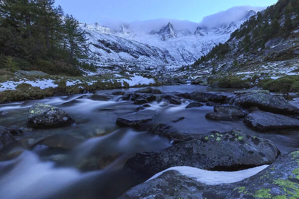 Mountain torrent at dusk in front snowy mountains, Valmasino, Valtellina, Lombardy, Italy, Europe