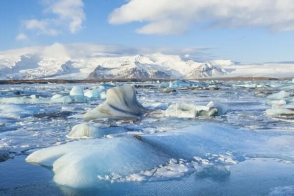 Mountains behind the icebergs locked in the frozen water of Jokulsarlon Iceberg Lagoon