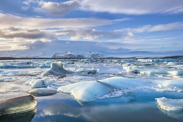 Mountains behind icebergs locked in the frozen water of Jokulsarlon Lagoon, Jokulsarlon