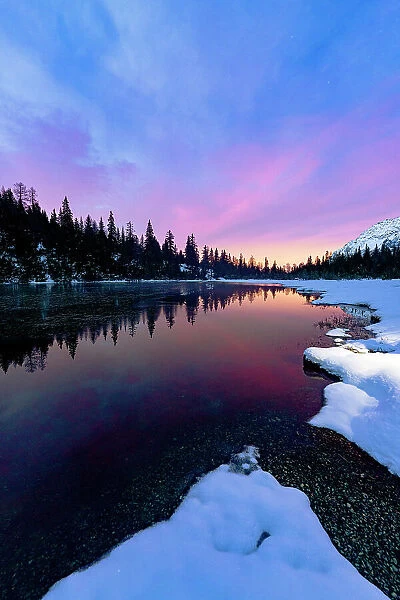 Multicolored sky at dawn reflected in the pristine water of lake Entova, Valmalenco, Valtellina, Sondrio province, Lombardy, Italy, Europe