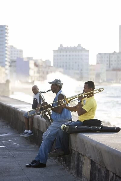 Musicians on The Malecon playing saxaphone and trombone with waves crashing against the shore in the background, Havana, Cuba, West Indies, Caribbean