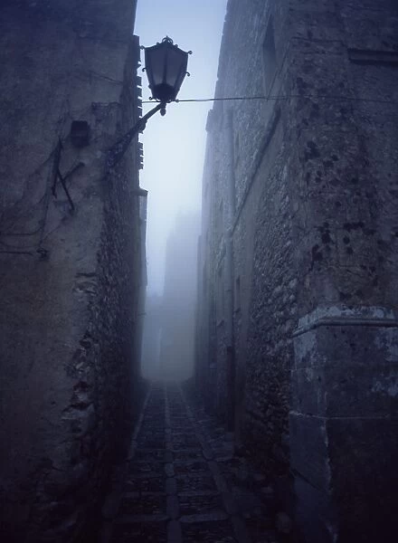 Narrow misty cobbled street