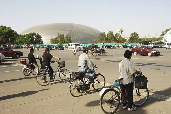 The National Theatre designed by the French architect Paul Andreu, and cyclists commuting in central Beijing, Beijing