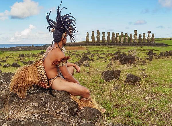 Native Rapa Nui man in tradititional costume and Moais in Ahu Tongariki, Rapa Nui National Park