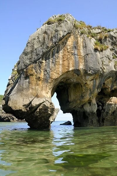 Natural rock archway carved by the sea through limestone rock at Cuevas del Mar (sea caves) beach, near Llanes, Asturias, Spain, Europe
